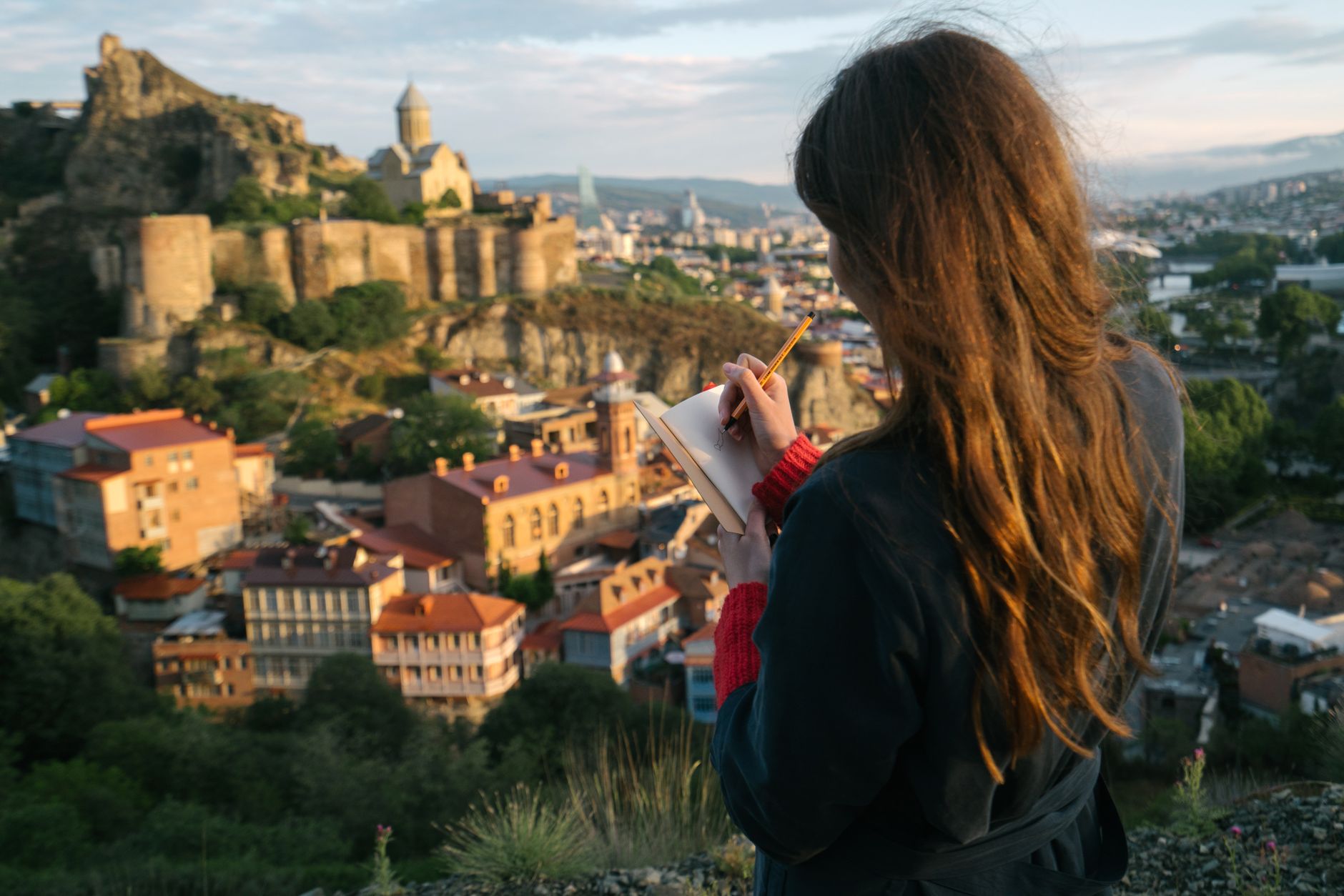 Travel author writing in notebook overlooking alpine peaks